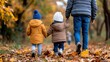 © angel_nt - A father holds hands with his two children as they stroll through a forest blanketed in vibrant autumn leaves, reveling in the beauty of the season and family bonds