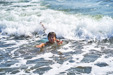 An 11 year old boy in having fun in the sea waves.