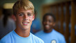 © JVLMediaUHD - Smiling Teenager in a Blue Shirt Stands in a School Hallway as a Classmate is Seen in the Background During Lunchtime