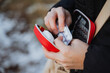 © Aleksey - A person is carefully taking a small pill out of a bright red case that is designed for holding medication and vitamins while ensuring to use their fingers and thumb appropriately