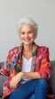 © Espresso - Smiling older woman with silver hair in colorful floral jacket, seated comfortably with a warm, inviting expression.