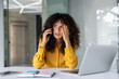 © Liubomir - Businesswoman in yellow shirt on phone, feeling stress at office desk with laptop. Emotional office scenario depicting communication difficulties and workplace pressure during crisis.