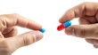 © Kharkovich - Hands holding a blue pill and a red and blue capsule on a white background