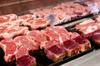 © isavira - Raw beef and pork cuts of meat into steaks behind the glass of the refrigerator on the counter in the supermarket