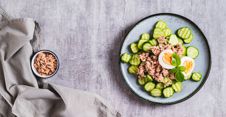 Wall Mural - Keto salad with tuna, cucumber, egg and basil in a bowl on the table top view web banner