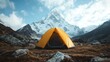 © JoxyAimages - An orange tent pitched on rocky terrain with a striking snowy mountain peak in the background under a cloudy sky, capturing the essence of adventure and serenity.