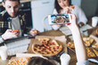 © BullRun - Unrecognizable woman taking photo of pizza during friends gathering