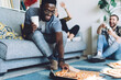 © BullRun - African American man taking piece of pizza while having fun with friends