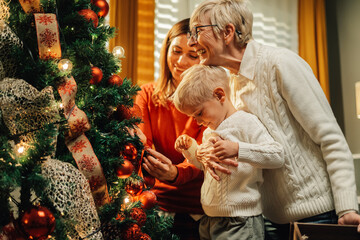 Wall Mural - Happy family decorating christmas tree at home