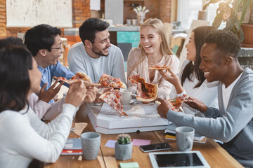 Office food delivery. Happy multiracial group of young workers eating pizza at office during lunch time