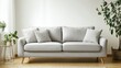 © G.Go - A large gray couch sits in a room with a potted plant and a few pillows