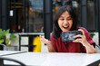 © M Alfan Setyawan - attractive asian woman excited playing game online using smartphone with raised hand sitting in outdoor cafe