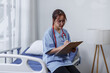 © David - Female doctor or nurse busy about analyzing healthcare treatment on medical documents on bed in hospital