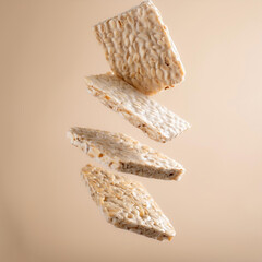 Raw tempeh or tempe. tempe slice floating or flying isolated on biege background