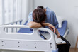 © David - Medical nurse is on bed in hospital sitting down a the hospital corridor in frustration and grief after failure and patient body condition