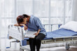 © David - Medical nurse is on bed in hospital sitting down a the hospital corridor in frustration and grief after failure and patient body condition