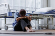 © David - Medical nurse is on bed in hospital sitting down a the hospital corridor in frustration and grief after failure and patient body condition