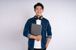 © STOCK88PHOTOGRAPHER - Portrait of Asian male student wearing cable and headphones , using laptop and  posing on white background