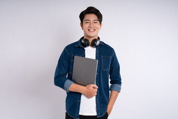 Portrait of Asian male student wearing  headphones , using laptop and  posing on white background