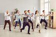 © Studio Romantic - Full length portrait of young funny business people doing corporate exercises standing at workplace in office. Team of smiling company employees exercising for health during a break from a work.