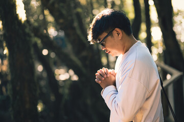 Man in white shirt praying to God outdoors in nature. Concept of prayer, faith, trust in God, obedience to God, meditation and focus on God.