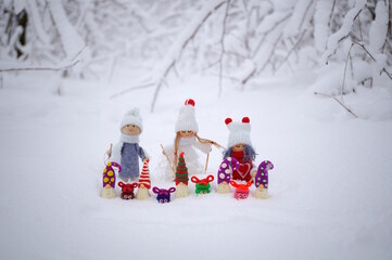 Wall Mural - Toy angels in knitted hats and scarves. There are dwarfs and gifts nearby. Christmas decorations. Snow background.