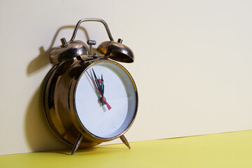 gold color vintage alarm clock against yellow