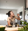 © Westend61 - Happy woman eating spaghetti and cooking food at home