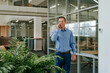 © Westend61 - Businessman talking on smart phone near glass wall in modern office