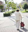 © zheng qiang - 秋の昼の住宅街で歩く一人のシニア女性の姿