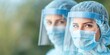 © Kamonwan - Two healthcare professionals in protective gear, focused expressions, outdoor setting.