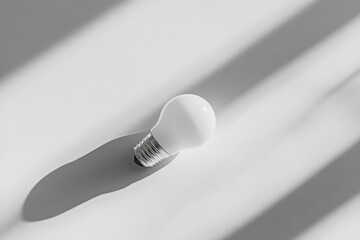 Fototapete - A simple white lightbulb on a plain surface captures attention with its crisp shadows. This composition highlights the interplay of light and form.