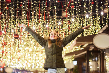 A teenage girl in a night city decorated for Christmas or New Year