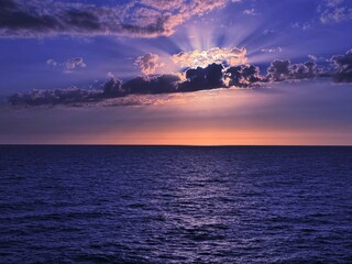 Wall Mural - Sunset clouds sky over dark blue sea. 