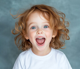 happy child with curly hair expressing joy in front of a neutral backdrop during daylight