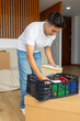 © ADDICTIVE STOCK - Trans man organizing belongings in new home