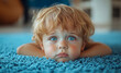 © Mark - Sad toddler boy lying on blue carpet, thoughtful expression, closeup of child with blue eyes, melancholic mood, emotional child portrait, innocence, young boy indoors, looking up
