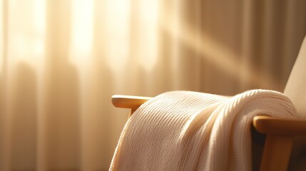 A cozy chair with a soft blanket draped over it, illuminated by warm sunlight coming through a window, creating a serene atmosphere.