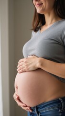 a close-up portrait captures a pregnant woman in midsection wearing jeans and a gray shirt embodying