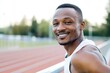 © Fotograf - A happy man smiles directly into the camera lens while standing on a track, possibly after a workout or achievement