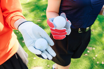 Two golfers prepare for a game on a sunny day, holding golf balls