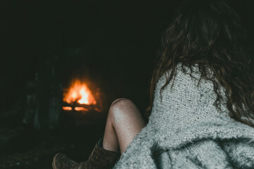 Wall Mural - A woman is sitting in front of a fireplace, with her legs crossed