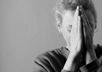 woman praying to god with hands together on grey black background with people stock photo stock image	