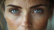 © Prostock-studio - A woman gazes directly into the camera showcasing her bright blue eyes and lightly freckled skin, illuminated by soft, natural light that highlights her unique features.