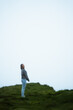 © Sergi - Woman standing in the middle of a cliff in a foggy day