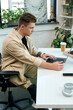 © Bliss - A young man with a prosthetic leg is intently working on his laptop in a bright and stylish office.