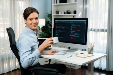 IT developer looking camera with holding coffee cup with online software on pc and laptop monitor beside, coding program on updated version application project creating new code system. Pecuniary.