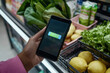 © Manu Prats - Mobile payment with fresh produce in background at grocery store