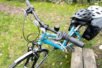 Shallow focus of the handlebars of a new women's hybrid, cross terrain bike seen leaning on a park bench during a ride out.