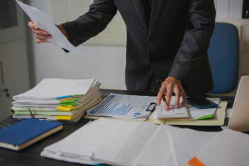 An Asian man works late at his desk papers, determined to meet his deadlines.